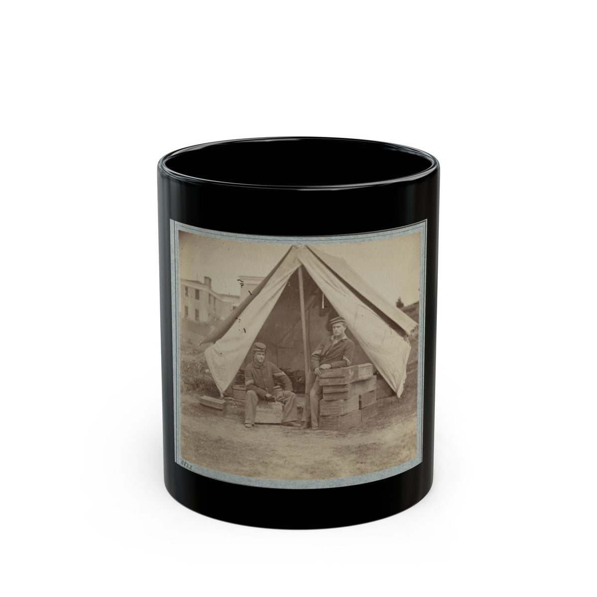 Sepia print showing two soldiers seated at a canvas tent beside stacked wooden ammunition crates.