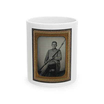 Antique tintype of a seated young man in a grey military coat holding a bayoneted rifle, in a gilt case.