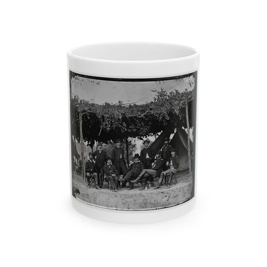 Black and white group portrait of nine uniformed officers beneath a leafy canopy in front of a canvas tent.