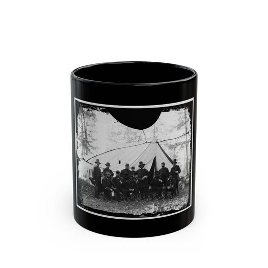 Cracked black and white group portrait of eleven uniformed officers before a large white conical tent among bare trees.