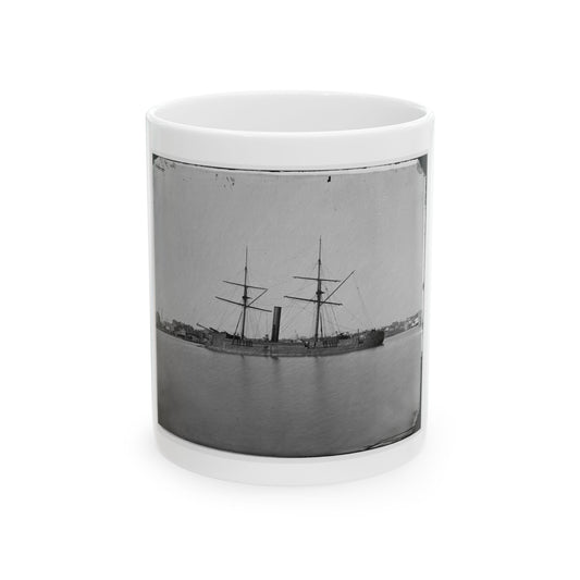 Black and white 1860s view of a two-masted steam warship with one smokestack on a calm river beside a town.