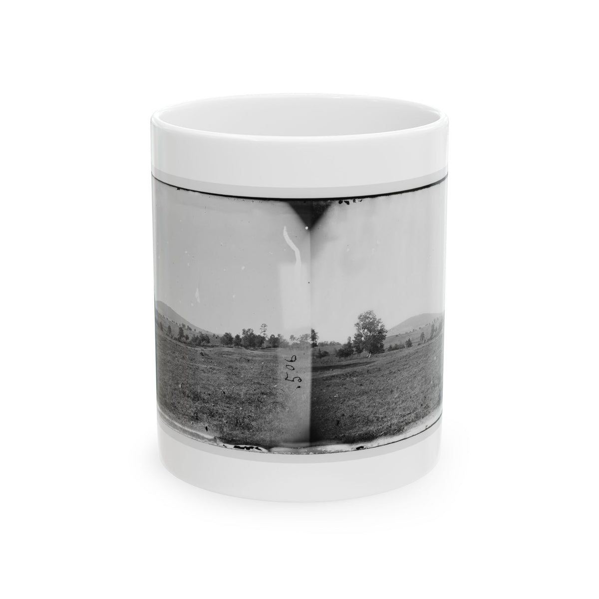 Black and white stereograph of an open grassy field with scattered trees and rolling hills under a pale sky.