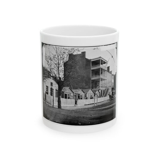 Black and white 1860s view of a multi-storey brick building with wooden balconies and a horse-drawn carriage.