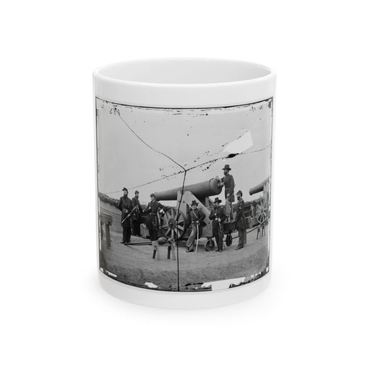 Cracked black and white view of seven uniformed officers posed around large cannons on a dirt fortification.