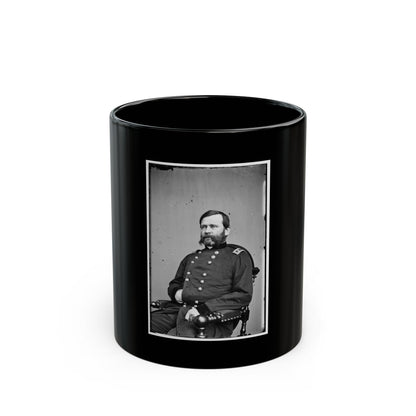 Black and white studio portrait of a seated bearded man in a dark military coat in a wooden armchair.