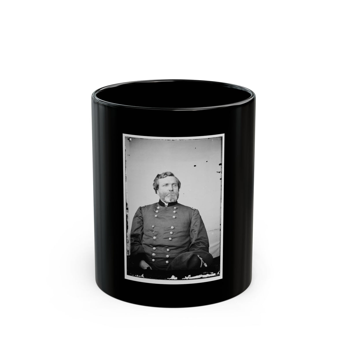 Black and white vintage portrait of a bearded officer in a dark double-breasted uniform, seated with a hat at his side.