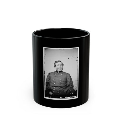 Black and white vintage portrait of a bearded officer in a dark double-breasted uniform, seated with a hat at his side.