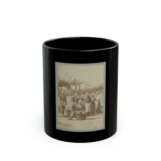 Sepia print showing six men in white caps and aprons standing around metal kettles at an outdoor camp kitchen.