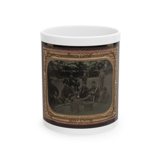Sepia tintype of seven soldiers resting on grass in camp, some holding sabres and tin cups, in a gilt case.