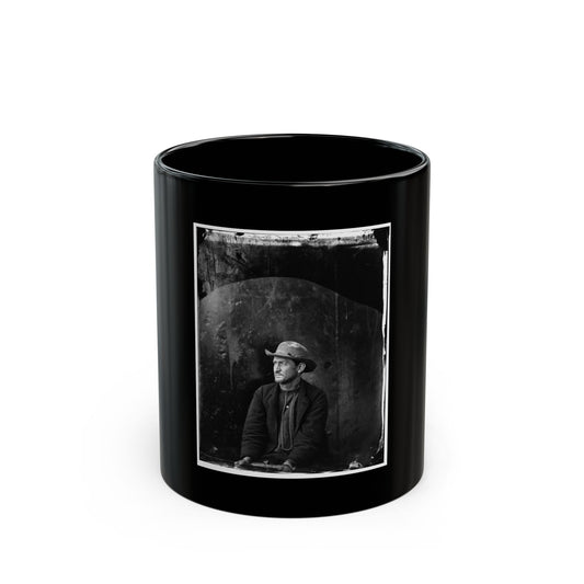 Dark black and white 1860s studio portrait of a seated bearded man in a slouch hat and work jacket.