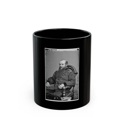 Black and white vintage portrait of a long-bearded man in a military coat seated in a carved wooden armchair.
