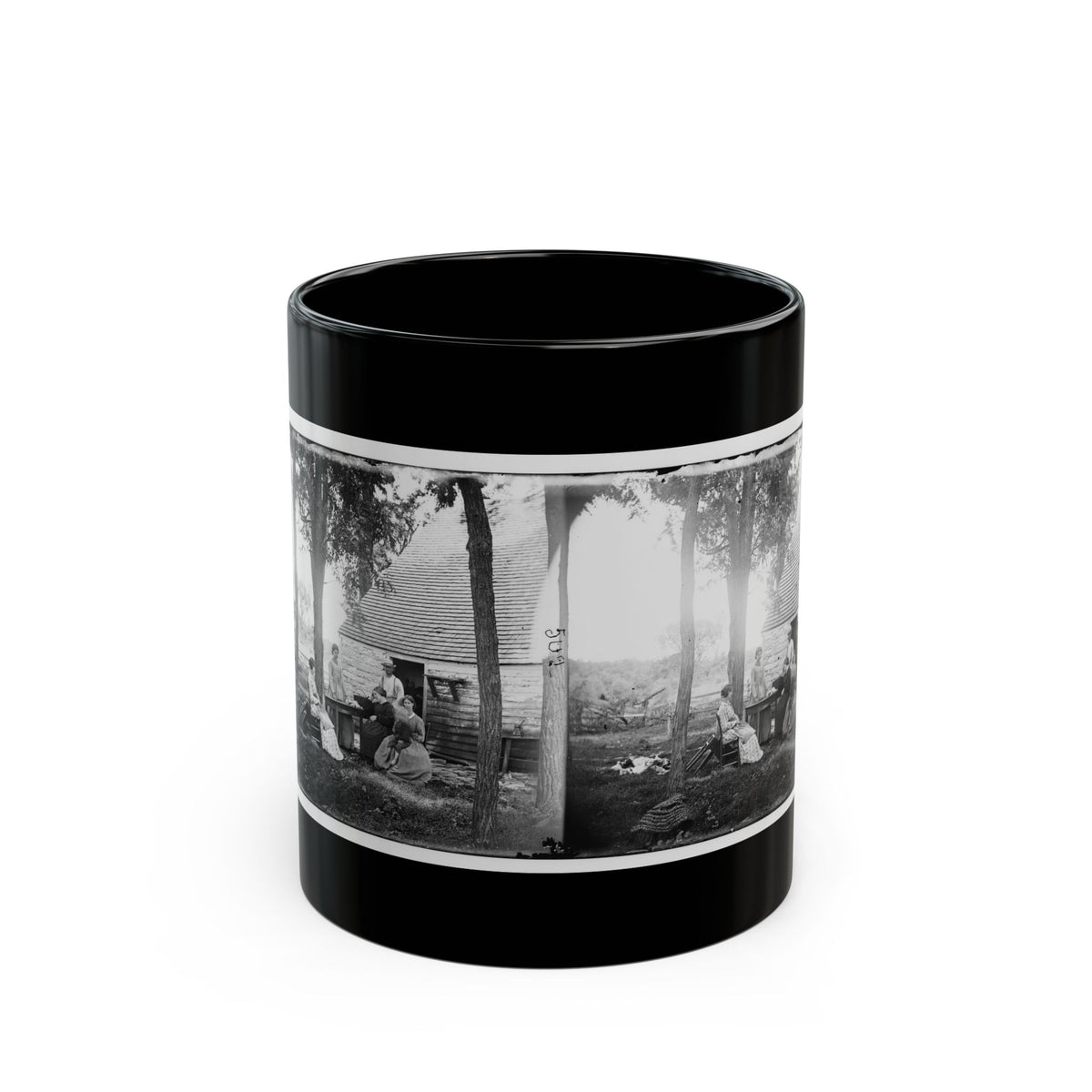 Black and white stereograph of a group of people gathered outside a stone cabin with a shingled roof under tall trees.