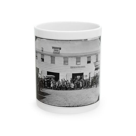 Black and white 1860s scene of a crowd of men before a two-storey wooden building with wagons at its doors.