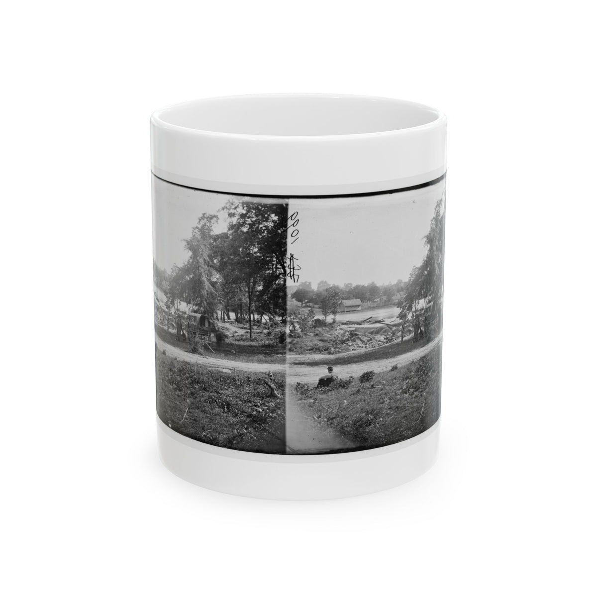 Black-and-white stereograph of a covered wagon by a riverbank among trees, with a seated figure in the grass in front.