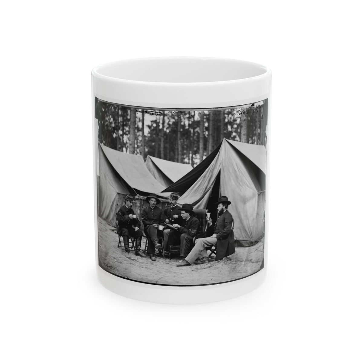 Black-and-white view of five men seated on folding chairs with cups before large canvas tents in a pine grove.
