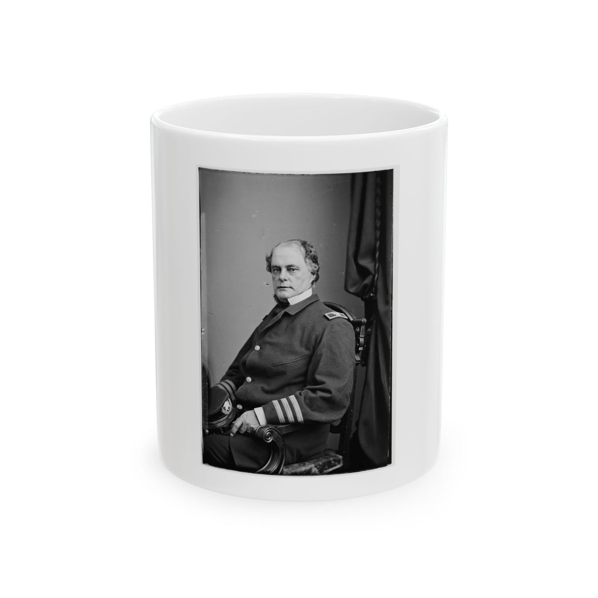Black and white portrait of a seated man in a dark military coat with striped sleeve cuffs beside a carved chair.