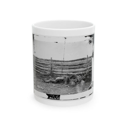 Black and white vintage view of three figures lying in grass beside a weathered split-rail fence.