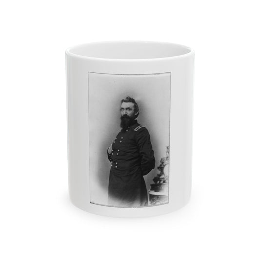 Black and white studio portrait of a bearded man in a double-breasted military frock coat beside an ornate pedestal.