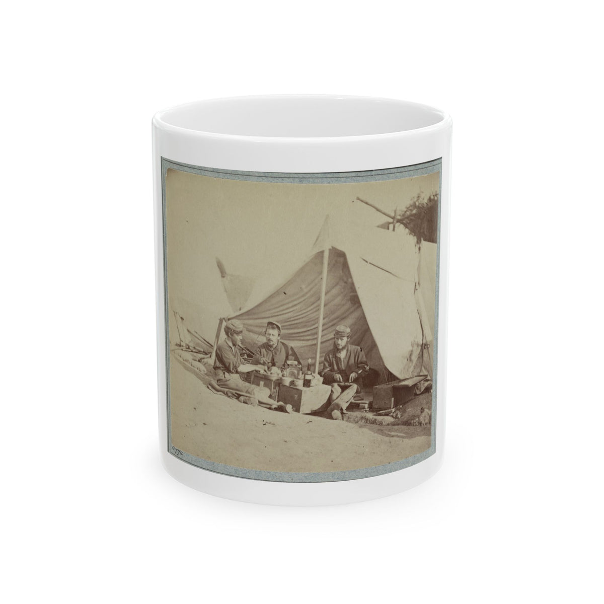 Sepia print showing three soldiers sharing a meal outside a canvas tent, beside a wooden chest and tin cups.