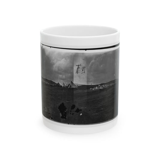 Black and white panoramic print of rows of conical tents across an open field below a cloudy sky.