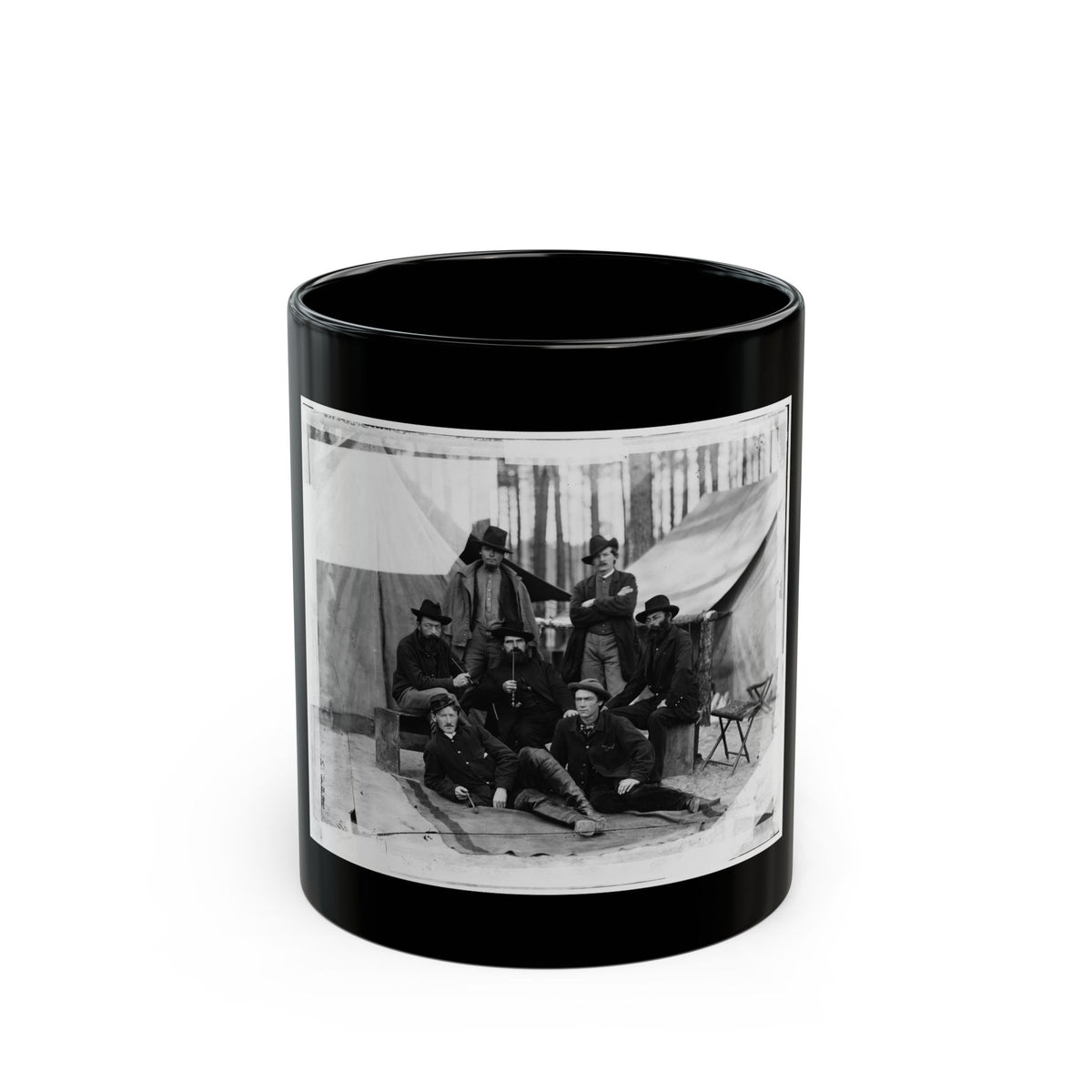 Black-and-white albumen view of seven men in coats, some smoking pipes, posed before canvas tents among pines.