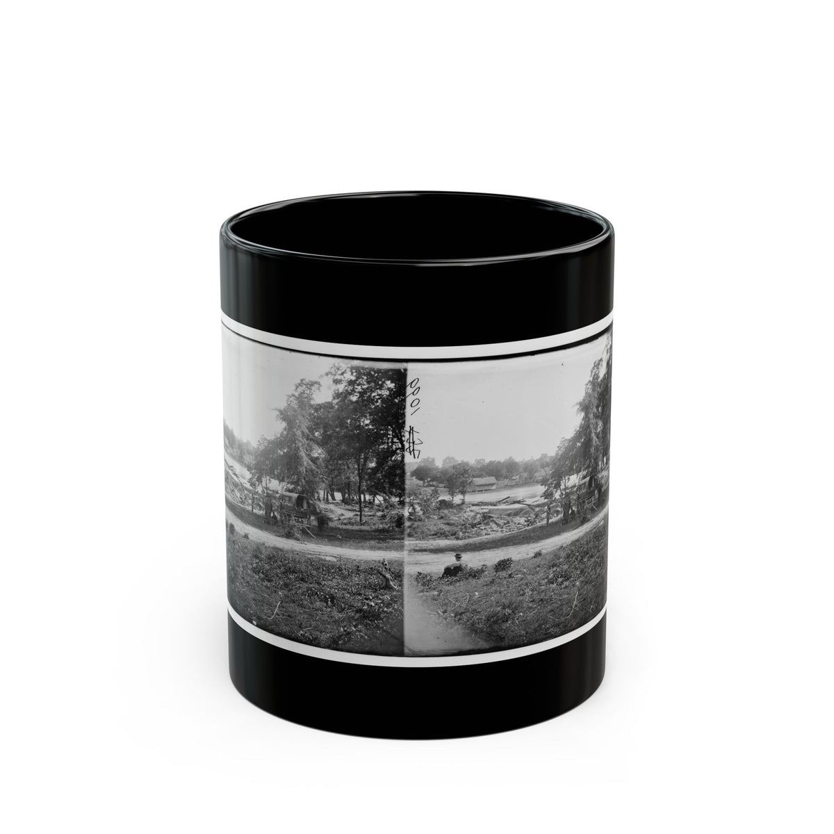 Black-and-white stereograph of a covered wagon by a riverbank among trees, with a seated figure in the grass in front.
