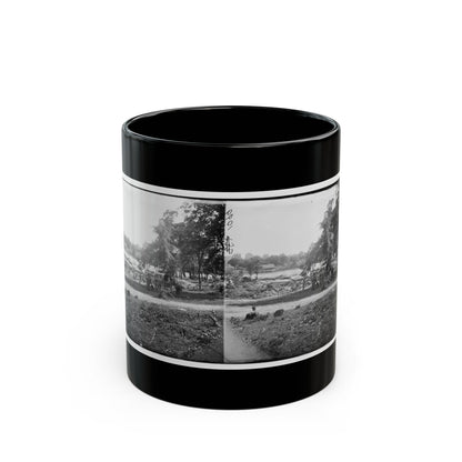 Black-and-white stereograph of a covered wagon by a riverbank among trees, with a seated figure in the grass in front.