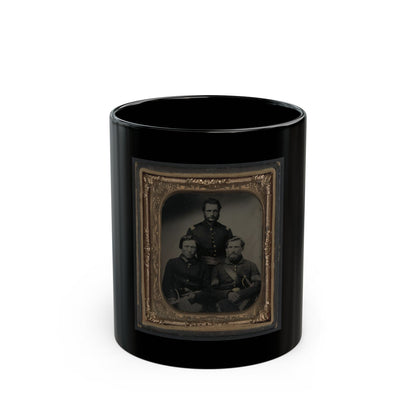 Black and white tintype of three men in dark uniform jackets, one standing and two seated, in a gilt frame.
