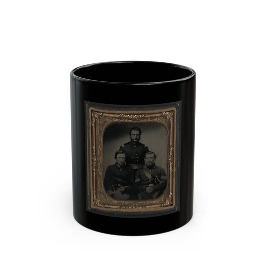 Black and white tintype of three men in dark uniform jackets, one standing and two seated, in a gilt frame.