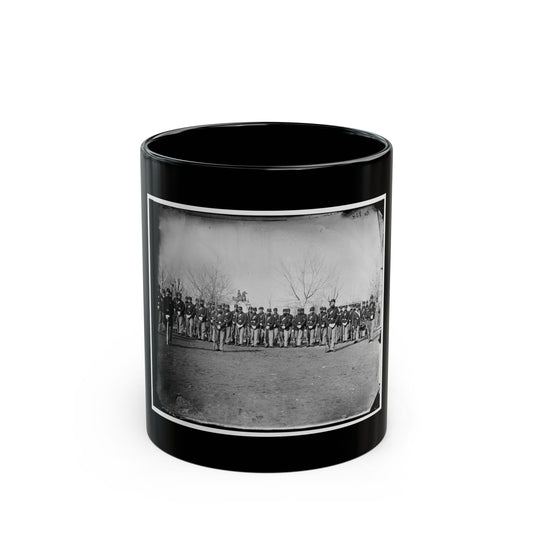 Black and white 1860s view of a uniformed infantry company standing in ranks with rifles on a dirt ground.