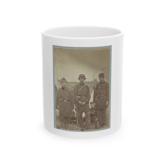 Sepia print showing three uniformed soldiers standing with rifles, with two seated men behind them.