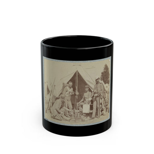 Sepia print showing four soldiers gathered around a cooking fire beside a canvas tent, with rifles stacked nearby.