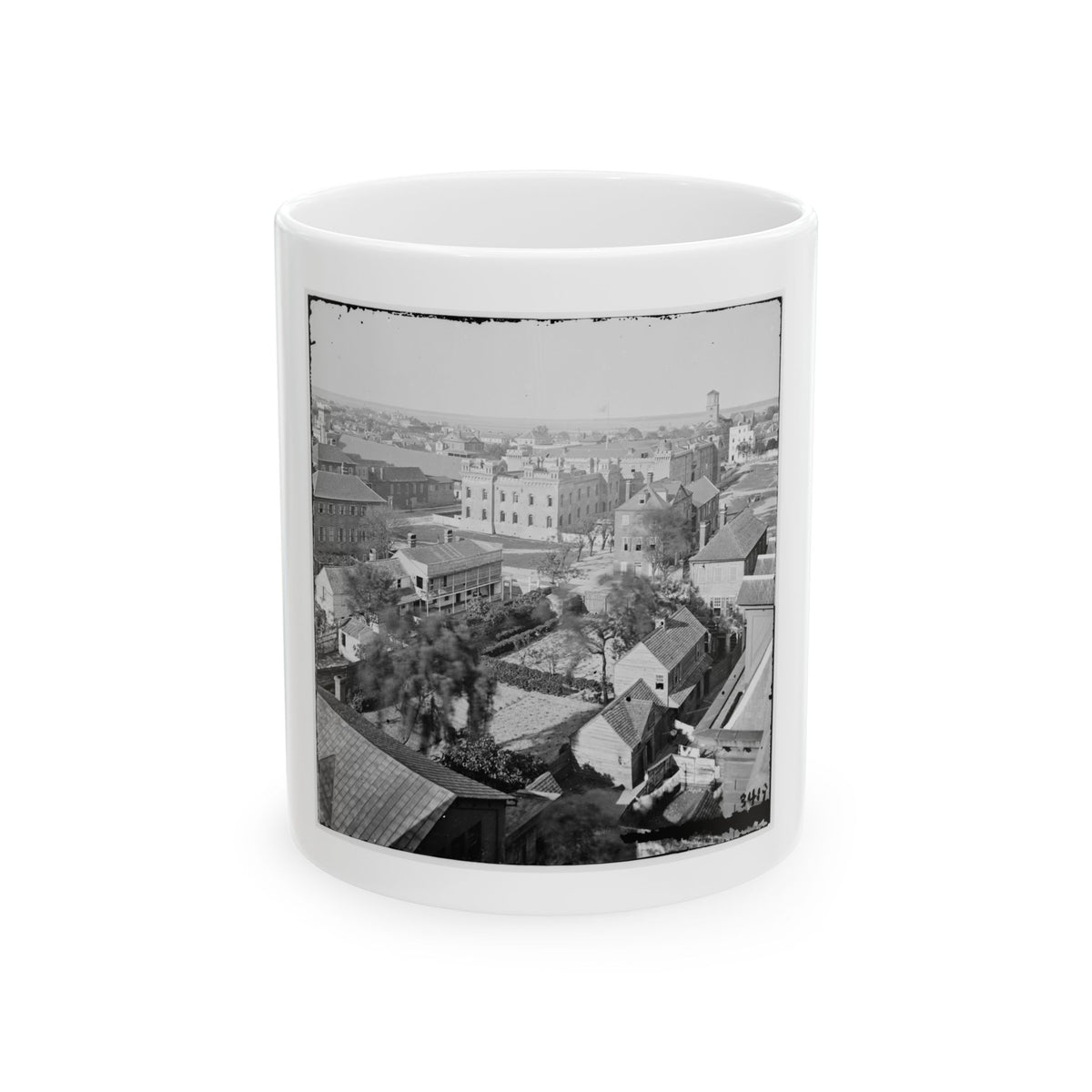 Black-and-white aerial view of a historic city with rooftops, walled gardens and a castellated stone building.