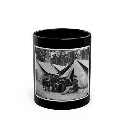 Black-and-white view of five men seated on folding chairs with cups before large canvas tents in a pine grove.