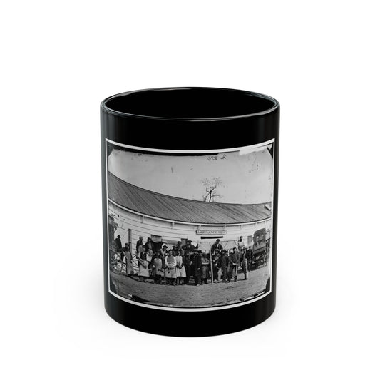 Black and white 1860s scene of workmen in aprons before a long wooden building beside an ambulance wagon.