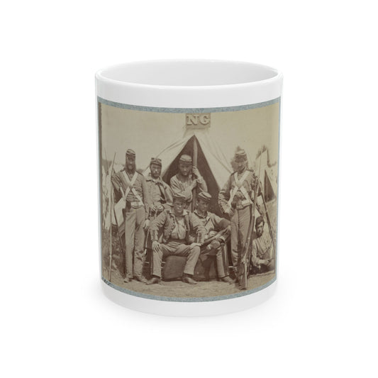 Sepia print showing seven soldiers with rifles posed in front of a canvas tent, some seated on a log.