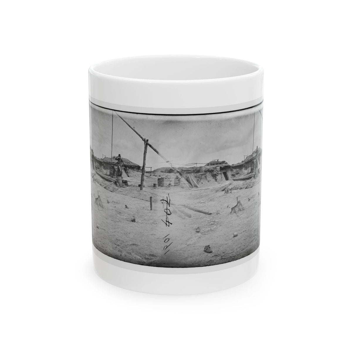 Black and white stereo view of a sandy military camp with earthen dugouts, barrels and a standing soldier.