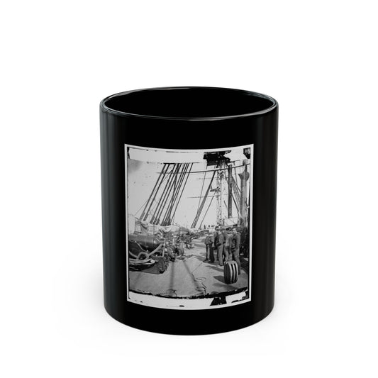 Monochrome view of sailors on a wooden warship deck beside a cannon, with coiled ropes and masts.