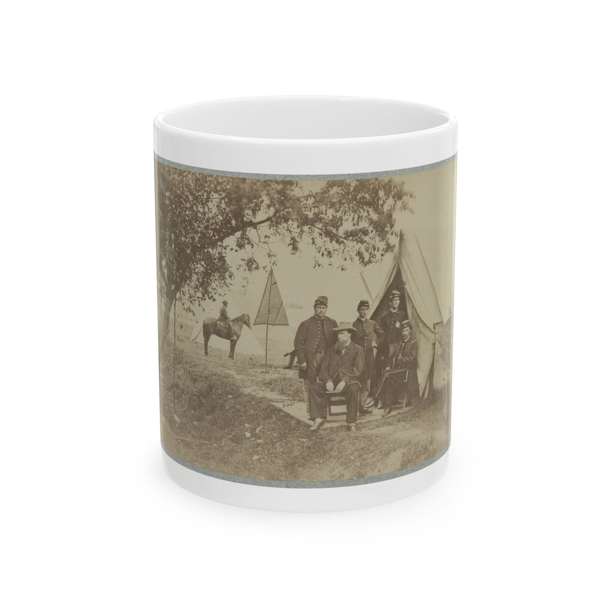 Sepia print of uniformed men posed before a canvas tent in a shaded camp, with a mounted rider nearby.