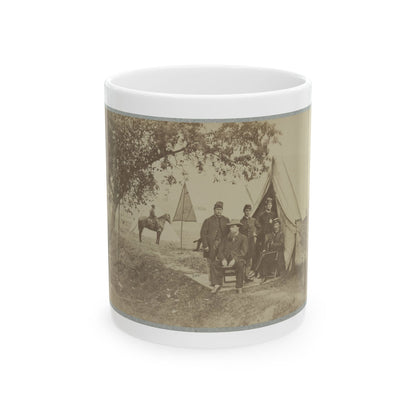 Sepia print of uniformed men posed before a canvas tent in a shaded camp, with a mounted rider nearby.