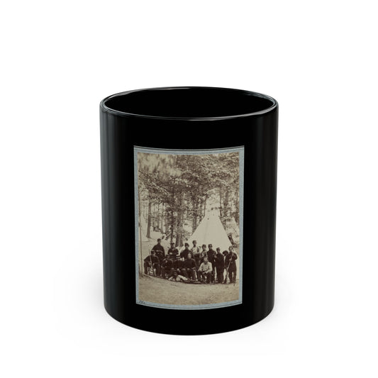 Sepia print showing about fifteen soldiers posed before a white conical tent beneath tall pine trees.