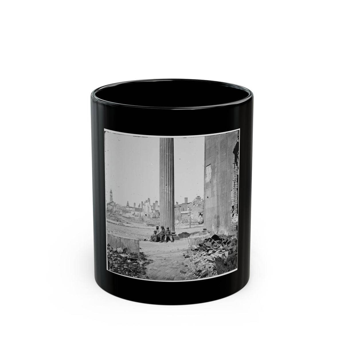 Black-and-white view of three children sitting by a tall fluted column amid ruined brick buildings and rubble.