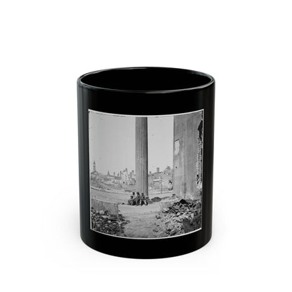 Black-and-white view of three children sitting by a tall fluted column amid ruined brick buildings and rubble.