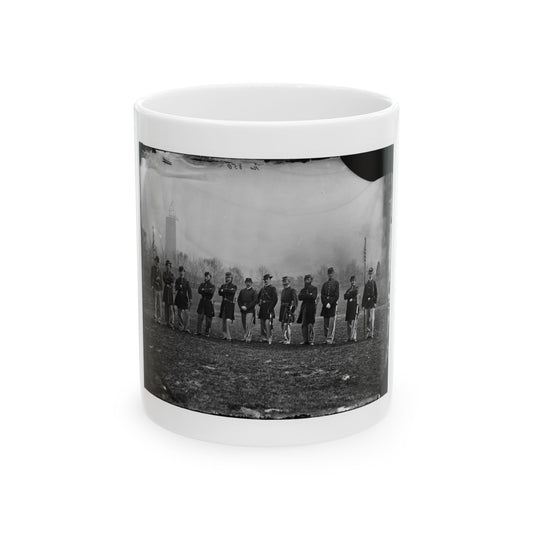 Black and white historical view of eleven uniformed men in a line on a grassy lawn, two holding flagstaffs.