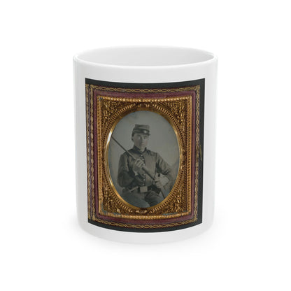Hand-tinted tintype of a young soldier in a kepi holding a rifle diagonally across his body, in a gilt oval case.