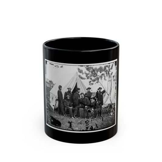 Black and white print of eight Civil War era soldiers posing in front of white canvas tents on grass.