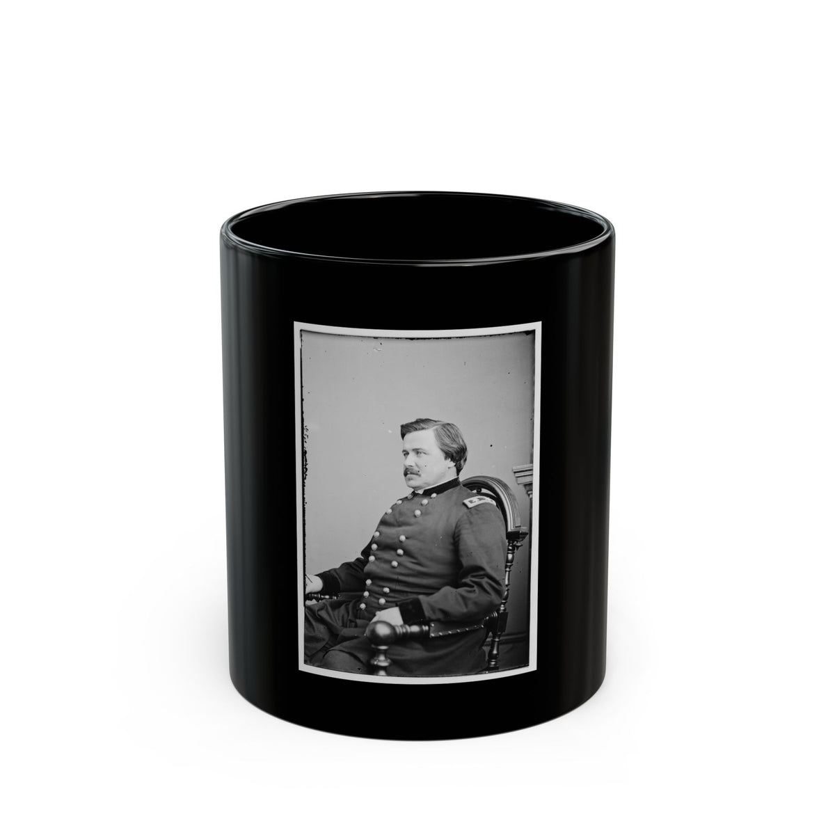 Black and white portrait of a man in a military coat seated in a carved wooden chair against a pale backdrop.