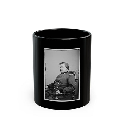 Black and white portrait of a man in a military coat seated in a carved wooden chair against a pale backdrop.