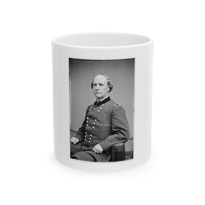 Black and white studio portrait of a seated balding man in a dark double-breasted coat with a velvet collar.