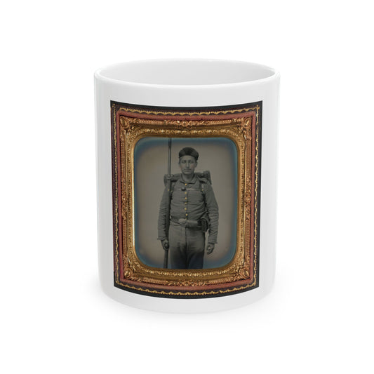Sepia tintype of a standing soldier in a grey uniform holding an upright musket, with a knapsack on his back.